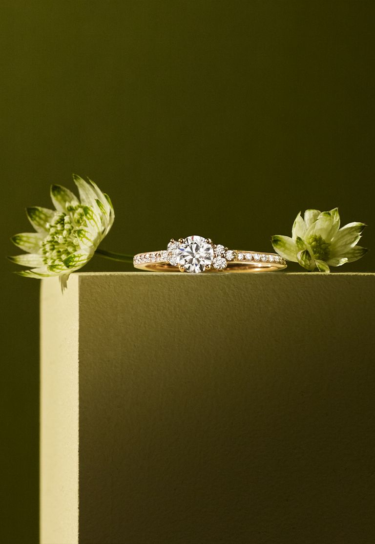 Woman relaxing in a lush green setting while wearing a stack of creations from Gemmyo's EverBloom collection.