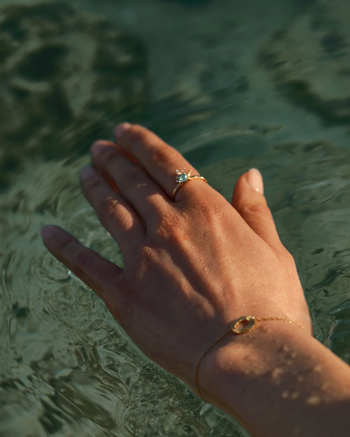 Hand eines Models, das den Little EverBloom Ring aus Roségold und Mint Turmalin und ein Entaille Rayons S Armband aus Roségold trägt.